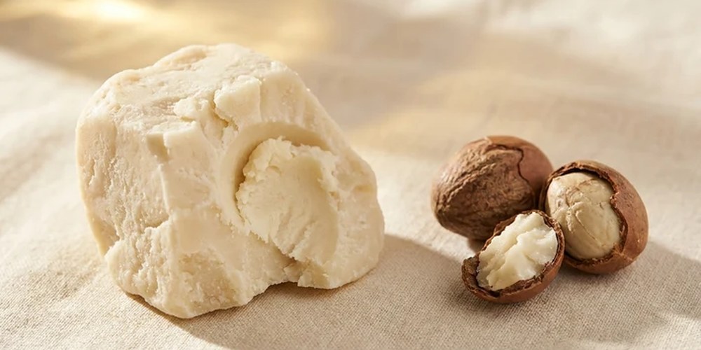 A block of raw shea butter beside cracked shea nuts